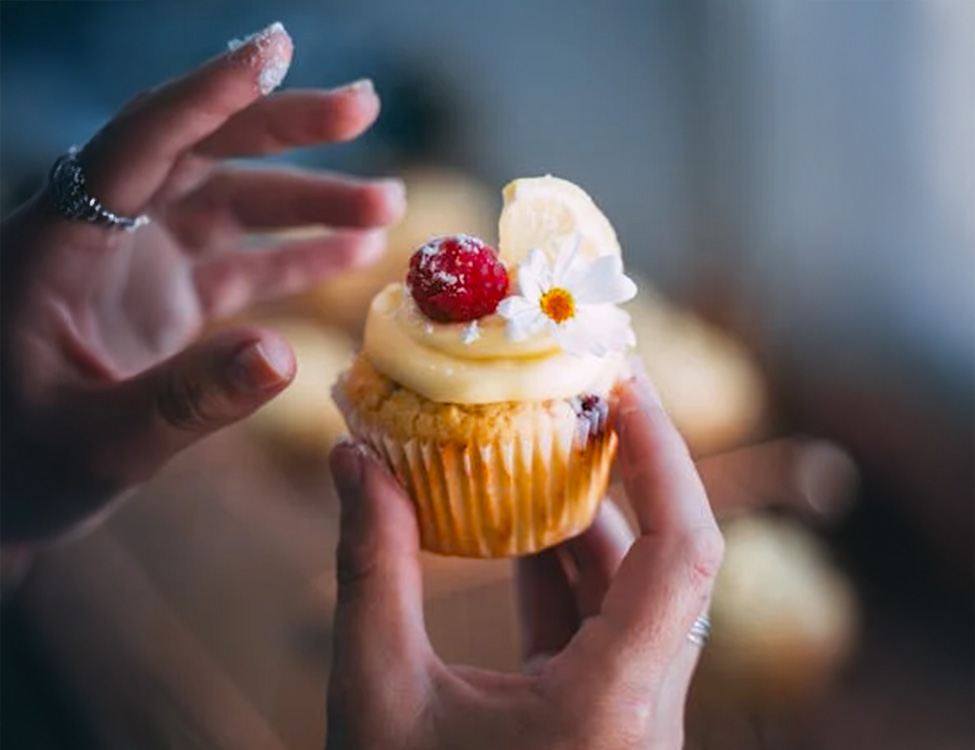 Image of someone holding a frosted cupcake